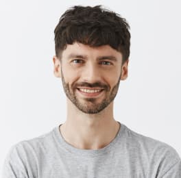 A smiling man with short dark hair and a short beard with a mustache